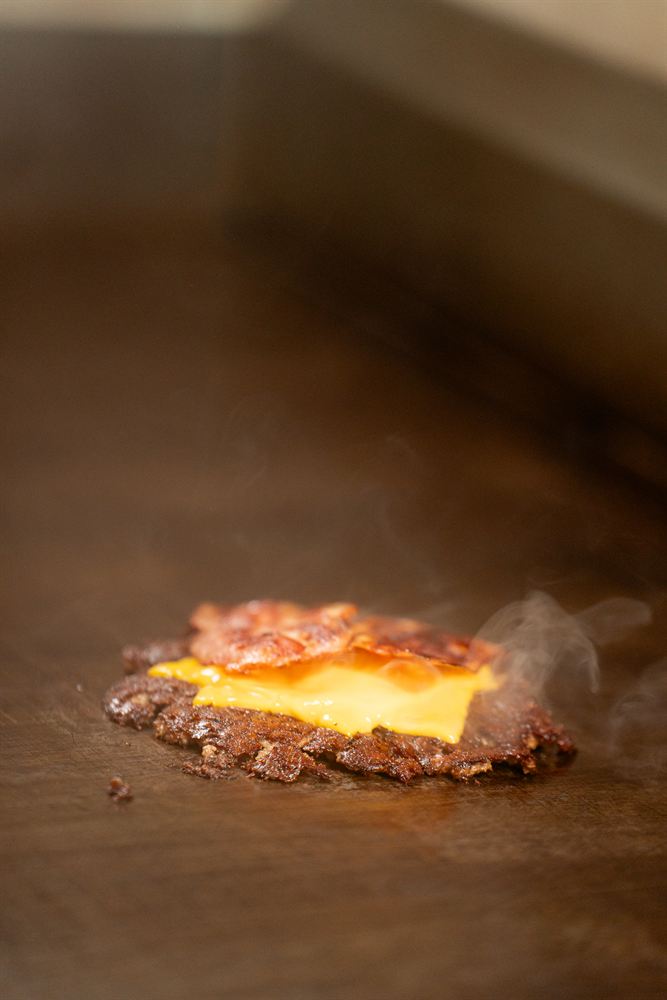 El bacon a la plancha coronando la carne con cheddar